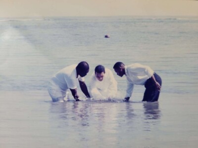 Bishop Charles Dufour performing a baptism in the ocean of Falmouth